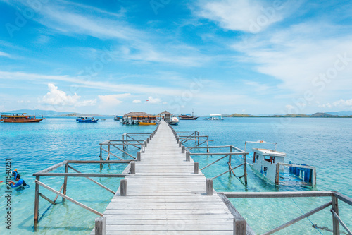View of the wooden pier from the coast of Kanawa Island with turquoise sea and tourist boats, Komodo Island (Komodo National Park), Labuan Bajo, Flores, Indonesia