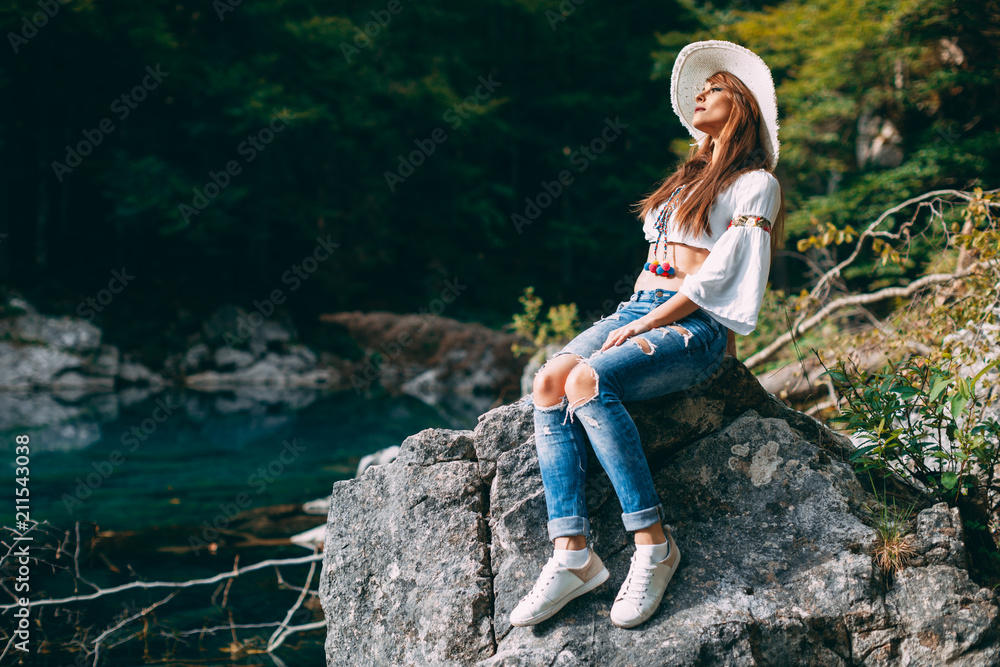 Young beautiful woman posing on a rock by the lake Young beautiful woman posing on a rock by the lake