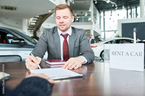 Man signing documents for new car with vehicle dealer © Seventyfour