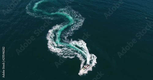 Top view fantastic figure of curve line in shape of dollar made with foamy speedboat traces on azure ocean water surface