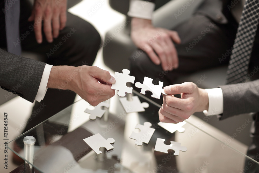 smiling businessman helping the partner to complete the puzzle smiling businessman helping the partner to complete the puzzle
