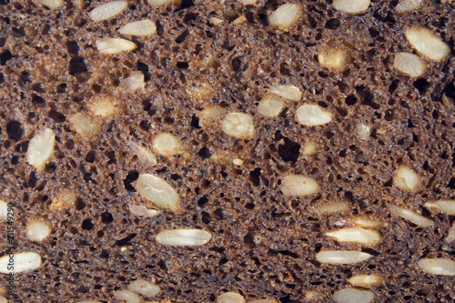 Porous section of dark bread with sunflower seeds closeup, may be used as background or texture