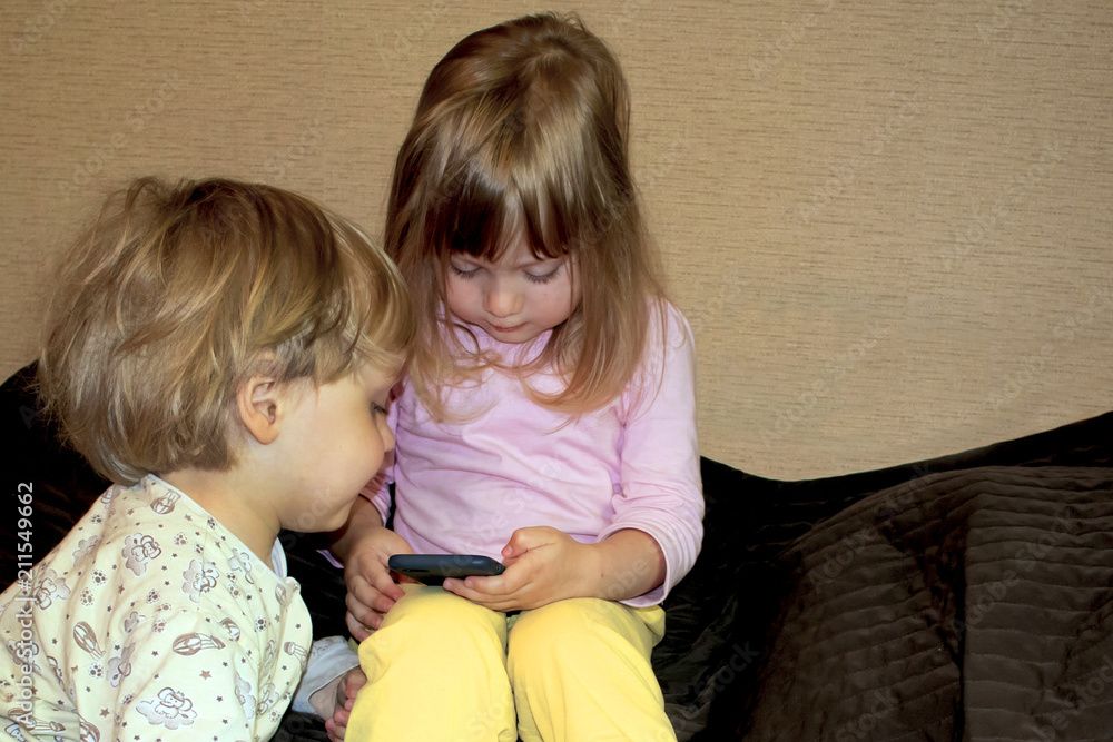 Little cute curious blonde twins watch cartoons on smartphone Little cute curious blonde twins watch cartoons on smartphone