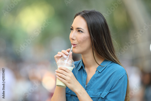 Woman drinking a smoothie looking at side