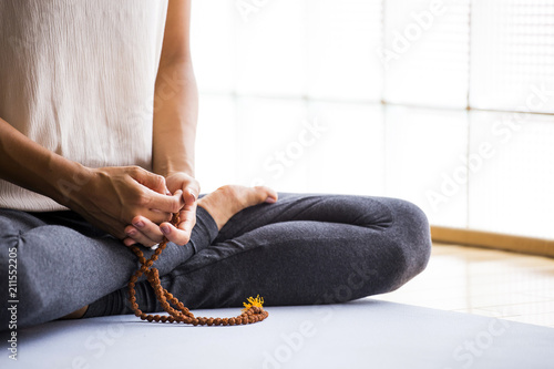 Closeup of a woman meditating with mala on hands 