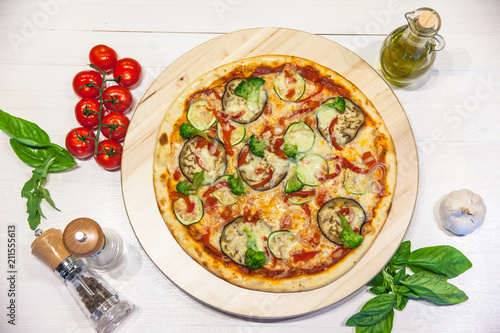appetizing vegetarian pizza with olive oil, spices and basil leaves on a white table, flat lay