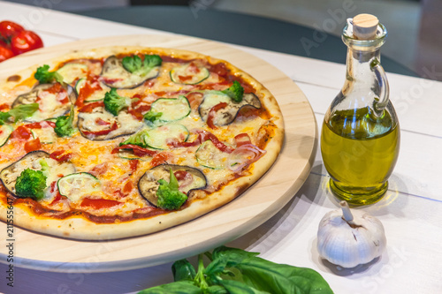 appetizing vegetarian pizza with olive oil on a white table