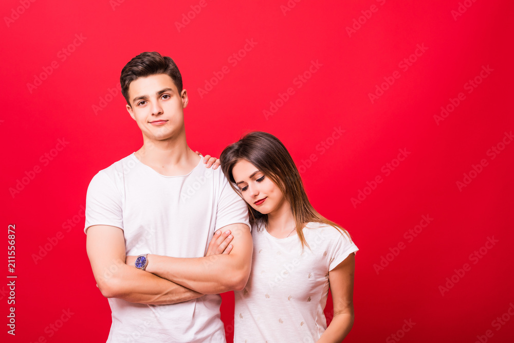 Happy couple embracing and looking camera on red background Happy couple embracing and looking camera on red background