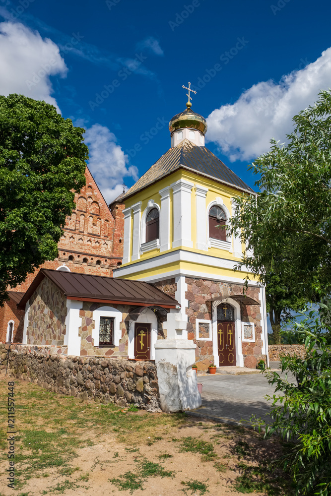 Old bell tower and 15th century  St. Michael fortified church at summer in Synkovichi, Grodno region, Belarus.
