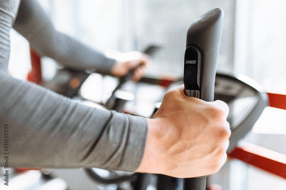 Training on a sports bike in the gym, hand close-up holding the handle of the bike