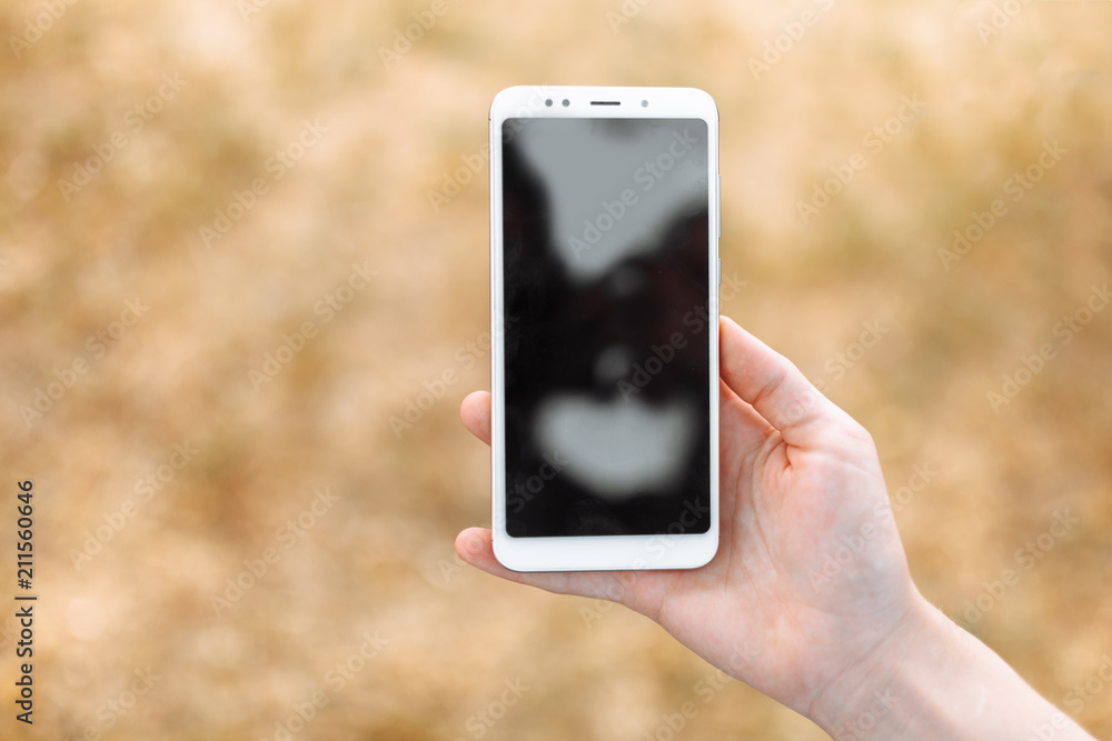 Close-up of hand holding phone on blurred, isolated place for text Close-up of hand holding phone on blurred, isolated place for text