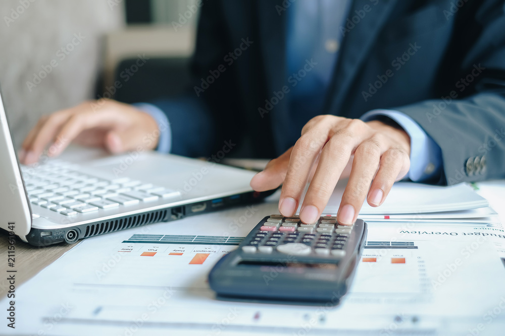 Businessman using calcultor for analysis maketing plan, Manager calculate financial report and graph chart. Business, Finance and Accounting concepts Businessman using calcultor for analysis maketing plan, Manager calculate financial report and graph chart. Business, Finance and Accounting concepts