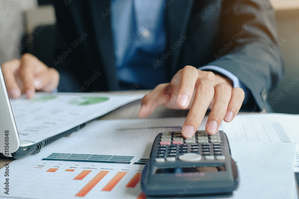 Businessman using calcultor for analysis maketing plan, Manager calculate financial report and graph chart. Business, Finance and Accounting concepts Businessman using calcultor for analysis maketing plan, Manager calculate financial report and graph chart. Business, Finance and Accounting concepts