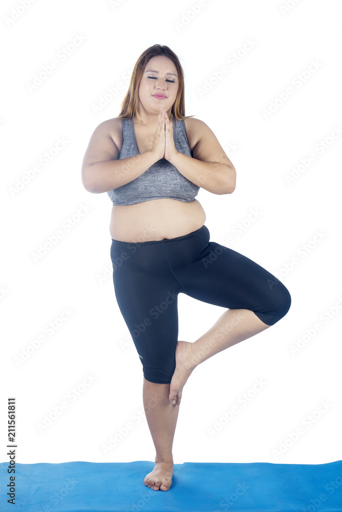 Fat woman exercising yoga in tree pose Stock Photo