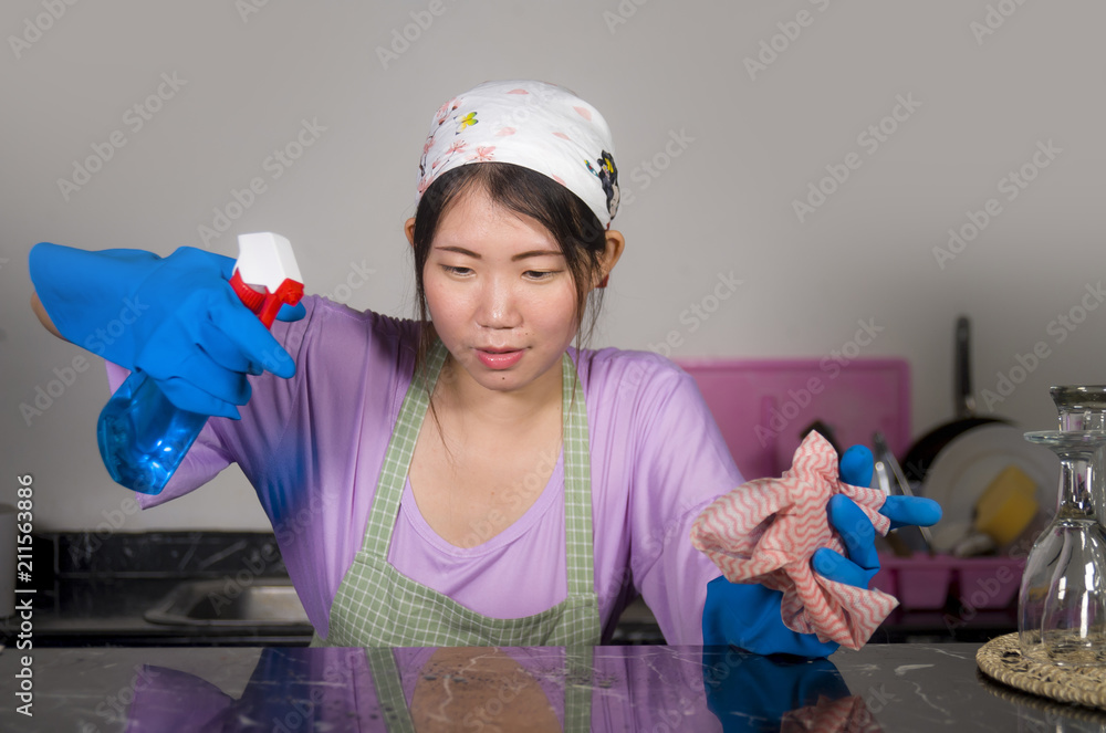 young beautiful and happy Asian Chinese woman cleaning and washing with spray bottle at home kitchen in rubber gloves enjoying domestic chores young beautiful and happy Asian Chinese woman cleaning and washing with spray bottle at home kitchen in rubber gloves enjoying domestic chores