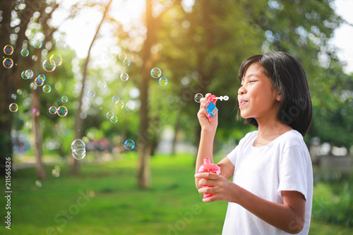 Little Asian girl blowing bubbles in the garden.