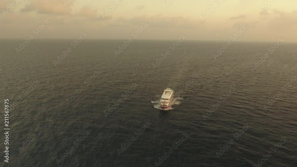 Aerial view of yacht or boat cruising at open sea in sunset Aerial view of yacht or boat cruising at open sea in sunset