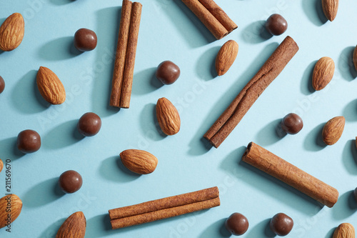 Chocolate balls  almonds  cinnamon sticks presented on a blue paper background with reflection of shadows. Flat lay