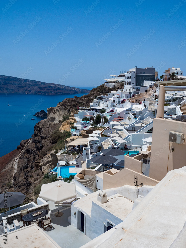 Scenic view of traditional cycladic Santorini houses on small street with flowers in foreground. Location: Oia village. Holidays background. Santorini, Greece, june 2018