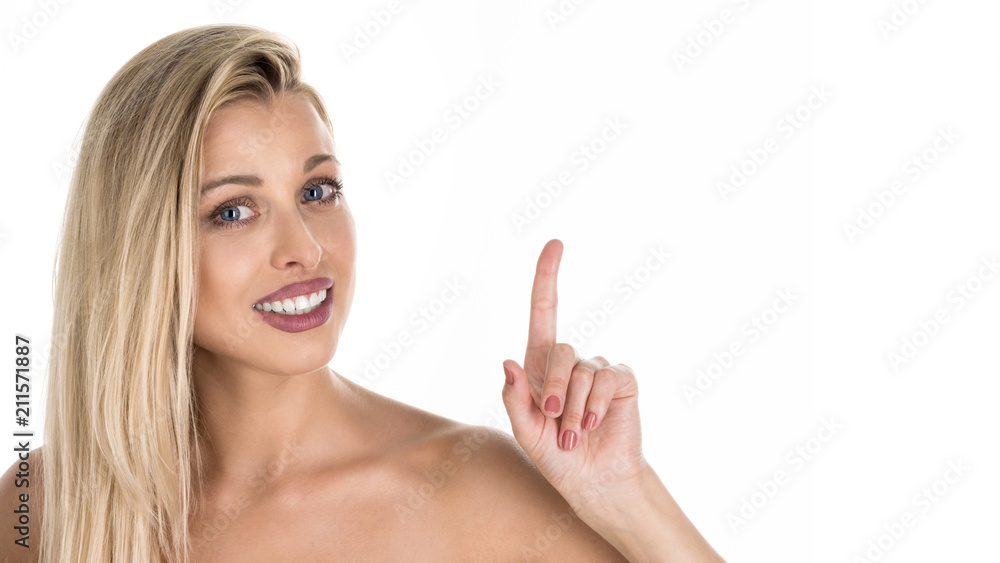 Close-up portrait of young woman smiling and showing thumb up, isolated white gray wall background. Smiling woman pointing with her finger.