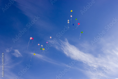 Multicolored balloons flying in the sky with cirrus clouds