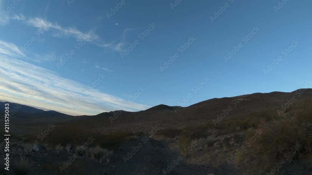 Stabilized camera movement gripped on a car at sunset golden hour. The Andes mountains on background. Van descending from mountains. Small shrubs on the sides of the gravel road. Mendoza, Argentina. Stabilized camera movement gripped on a car at sunset golden hour. The Andes mountains on background. Van descending from mountains. Small shrubs on the sides of the gravel road. Mendoza, Argentina.