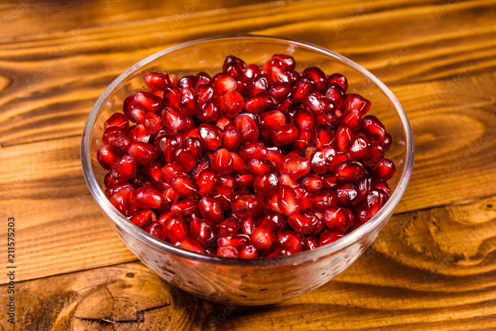 Seeds of the garnet fruit in glass bowl on wooden table Seeds of the garnet fruit in glass bowl on wooden table