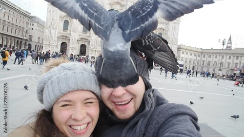 Happy tourists and pigeons taking a self portrait with phone in front of Duomo cathedral,Milan. Winter travel concept
