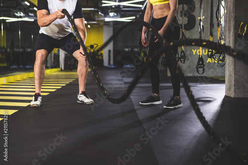Man gesticulating hands with equipment while standing near female in keep-fit studio