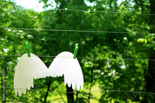 Wings of an angel hang on the background of a summer garden on a washing line
