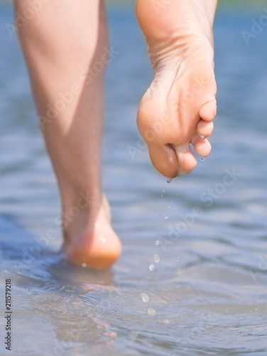 Wallpaper Mural The girl's legs are on the water on the beach close-up.
 Torontodigital.ca