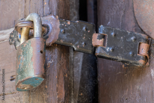Close up of padlock and old hasp on an old wooden door. Locked old door with a cobweb.