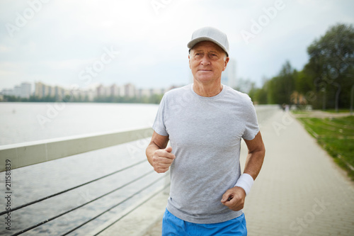 Active senior man in sportswear practicing jogging in urban environment in the morning © pressmaster