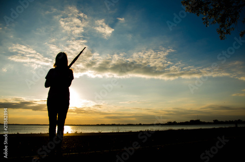 Sad woman standing on the road with sunset background.