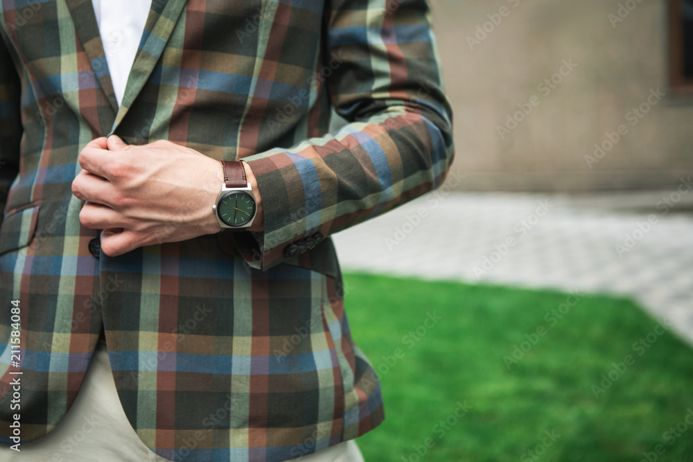 Close up of male arm buttoning his fashionable jacket. Man is standing outdoor with watch on wrist. Copy space 