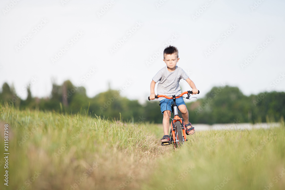 The boy is riding a bicycle in the field.