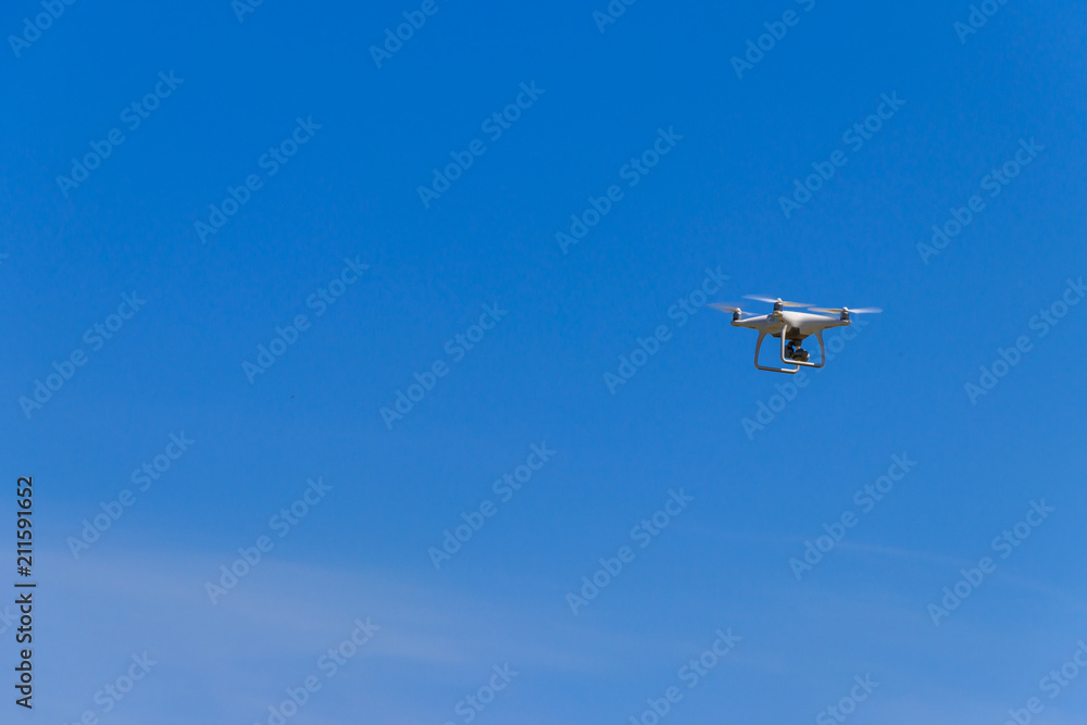Drone with camera flying in blue sky Drone with camera flying in blue sky