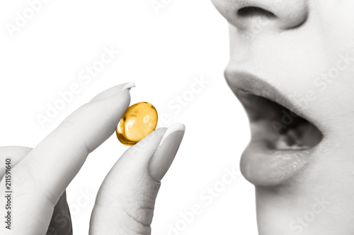 Close-up shot of woman brings the pill to her mouth. photo