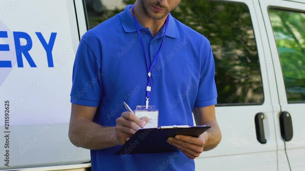 Delivery man filling in guarantee sheet of delivered goods staying near car Delivery man filling in guarantee sheet of delivered goods staying near car
