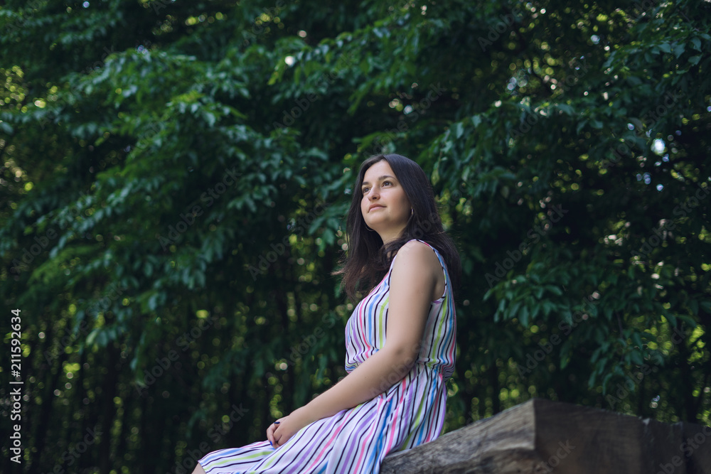Young woman sitting on bench in summer forest. Young woman sitting on bench in summer forest.