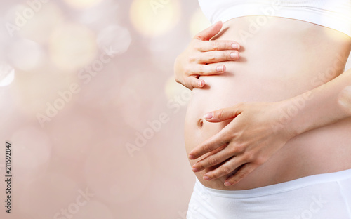 Fotografie Young pregnant woman caress belly. Maternity concept.