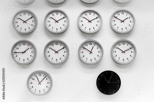 Many White clock and a black classic round wall clock . Different concepts of time