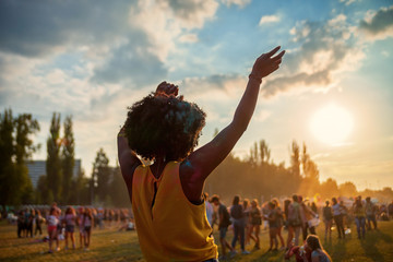 Young African American woman dancing at summer holi festival, back view