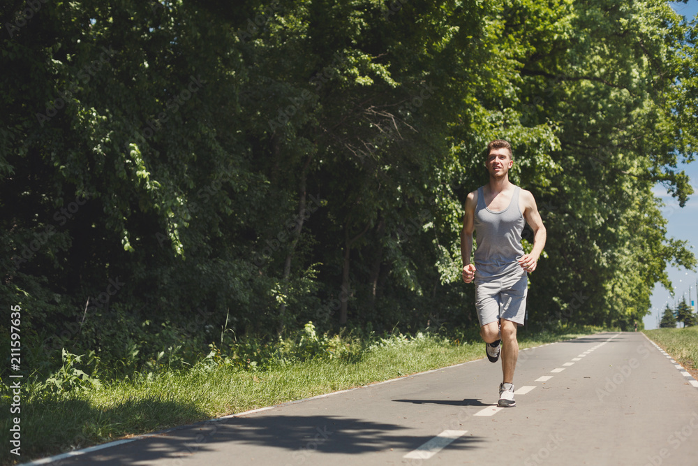 Young man jogging on treadmill in park, copy space Young man jogging on treadmill in park, copy space