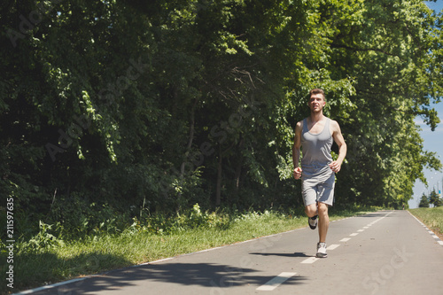 Young man jogging on treadmill in park, copy space