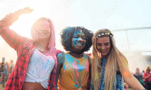 Multiethnic group of friends with colorful powder on clothes and bodies at summer holi festival having fun together