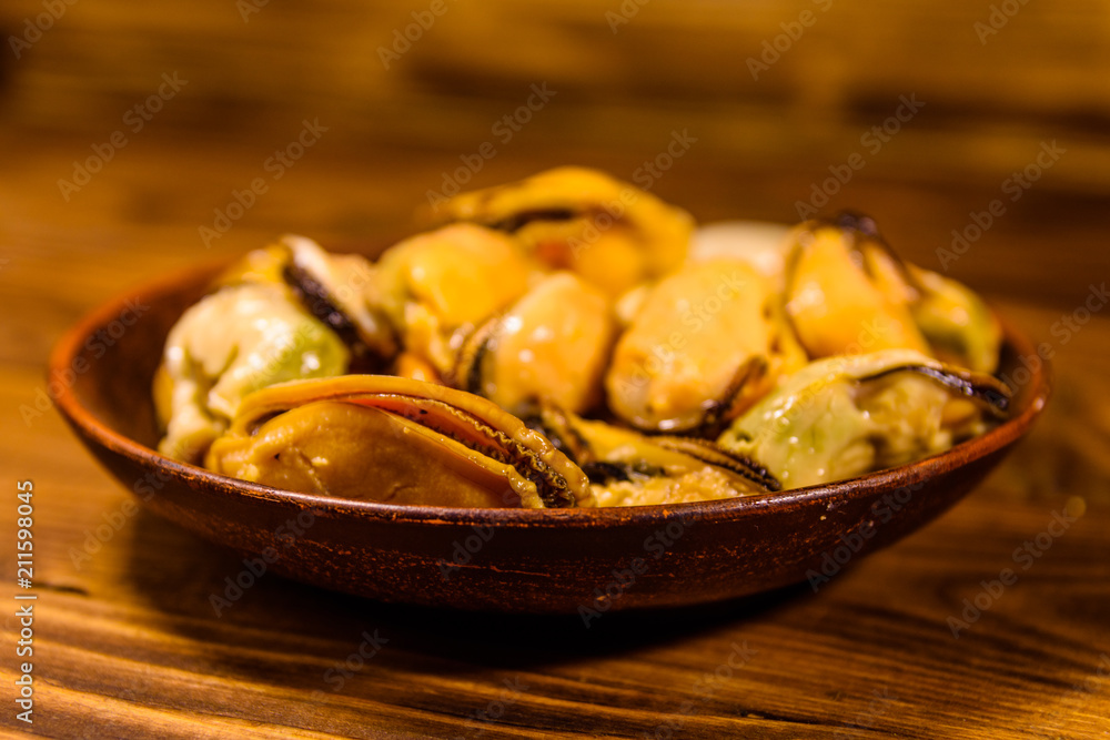 Fototapeta premium Ceramic plate with prepared mussels on wooden table