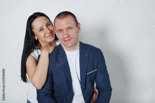 Picture of happy young loving couple standing over grey wall.