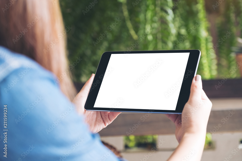 Mockup image of woman holding black tablet pc with white blank desktop screen with green nature background