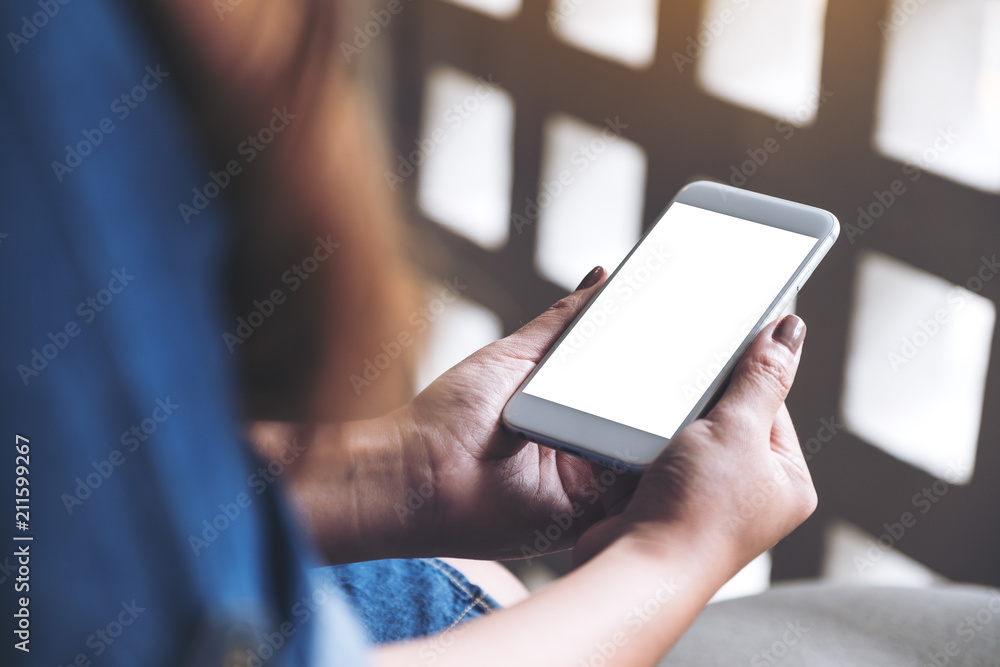 Mockup image of a woman holding white mobile phone with blank desktop screen in cafe Mockup image of a woman holding white mobile phone with blank desktop screen in cafe